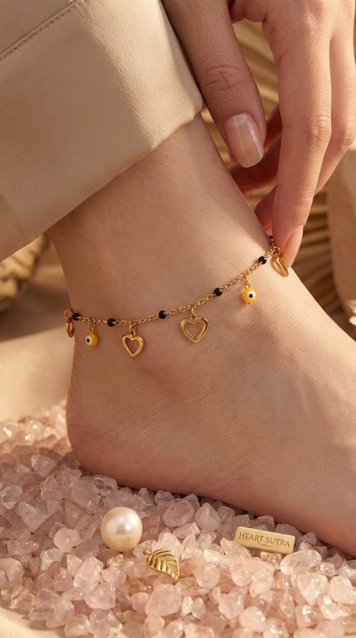 Gold-tone anklet with black beads, open hearts and yellow evil eye charms