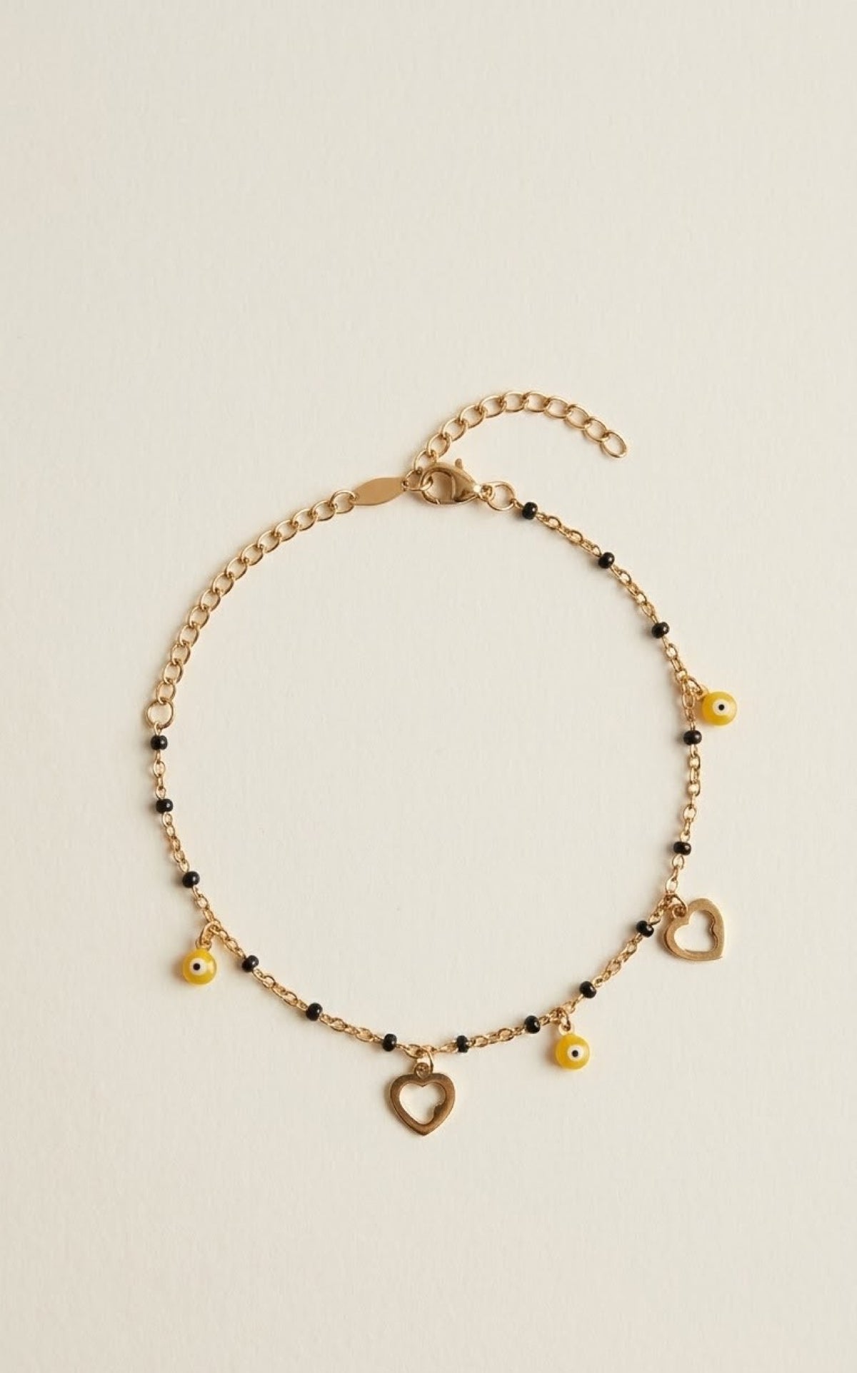 Gold-tone anklet with black beads, open hearts and yellow evil eye charms - view 2