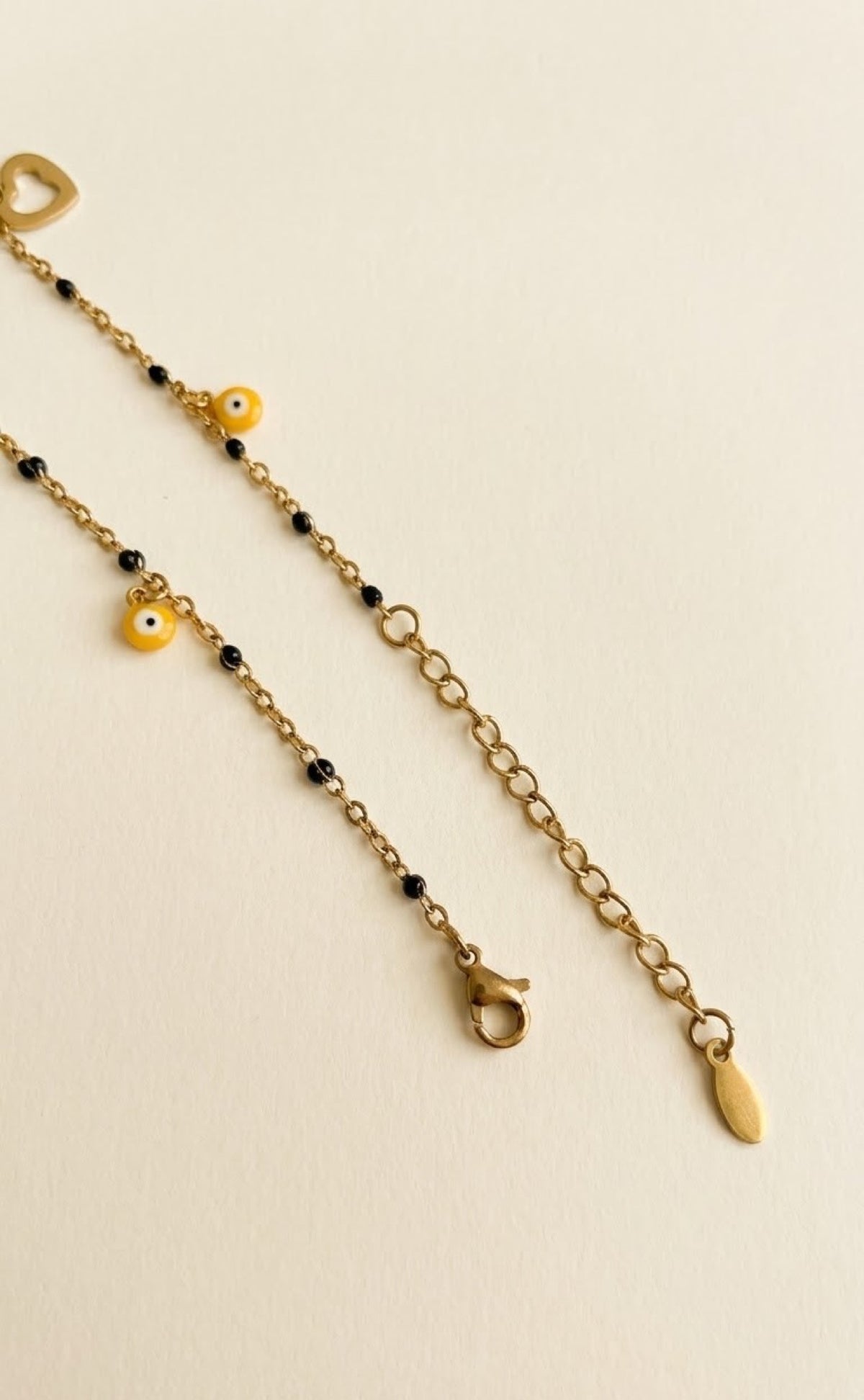 Gold-tone anklet with black beads, open hearts and yellow evil eye charms - view 3