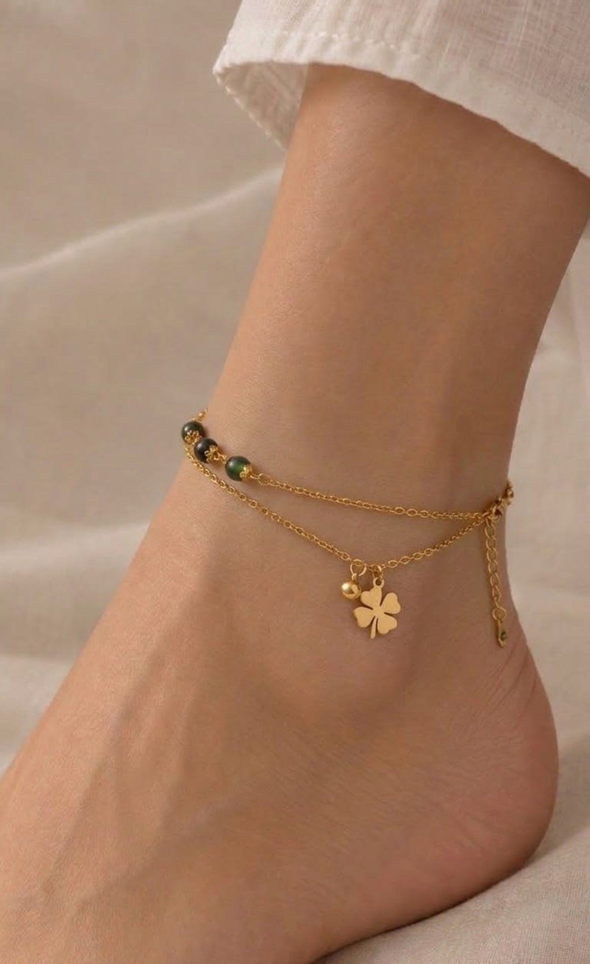 Gold-tone double-layer anklet with dark green beads and four-leaf clover charm
