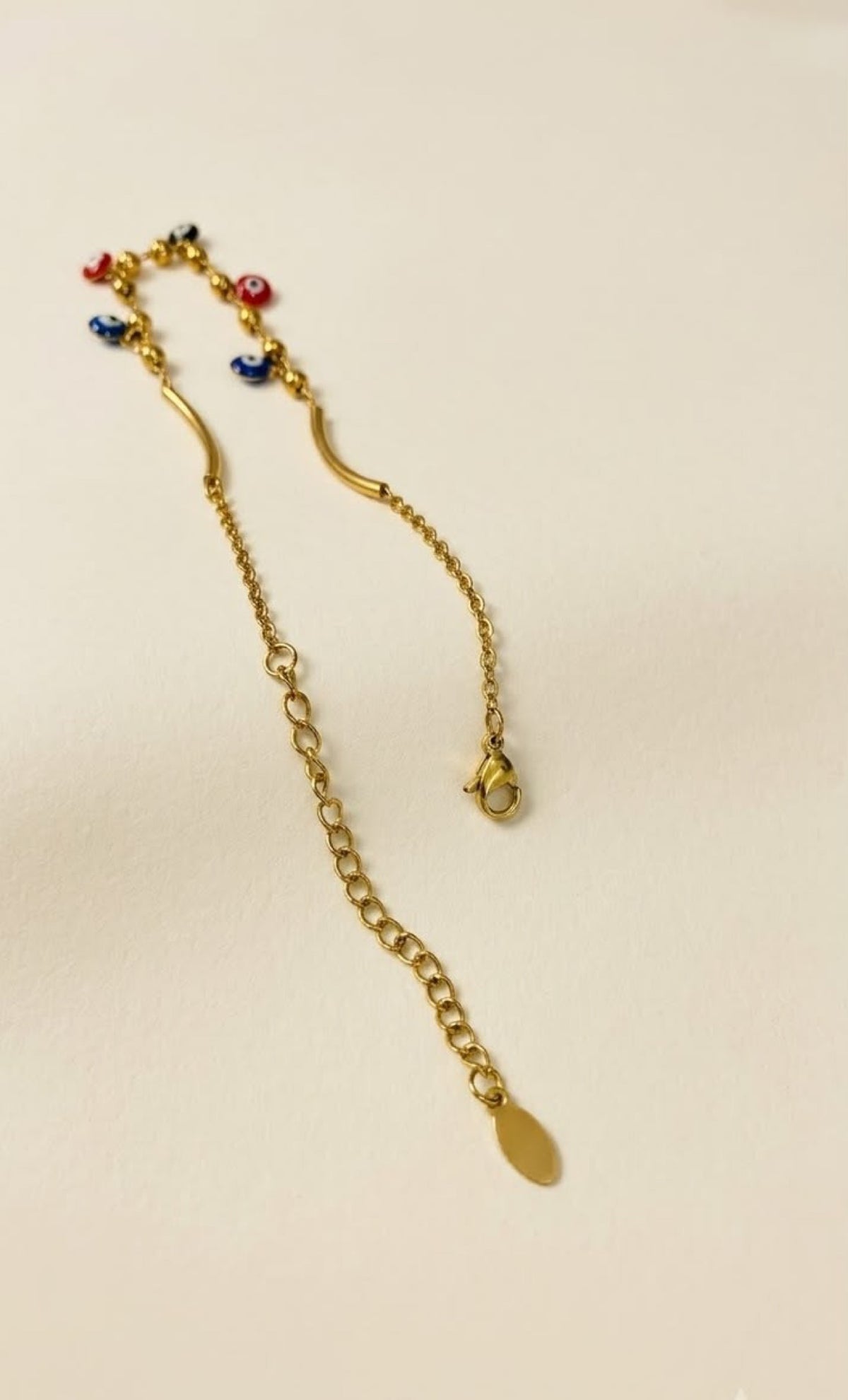 Pair of gold-tone anklets with curved bars and blue, red and black evil eye drops - view 3