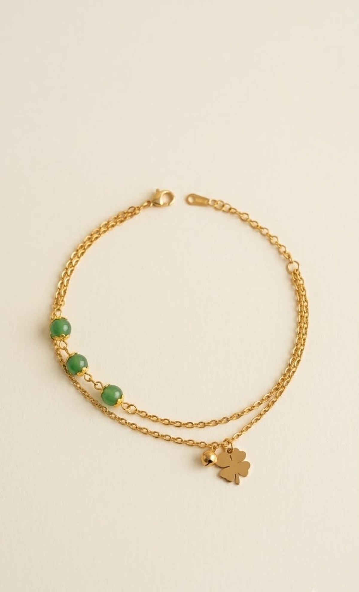 Gold-tone two-strand anklet with jade-green beads and four-leaf clover