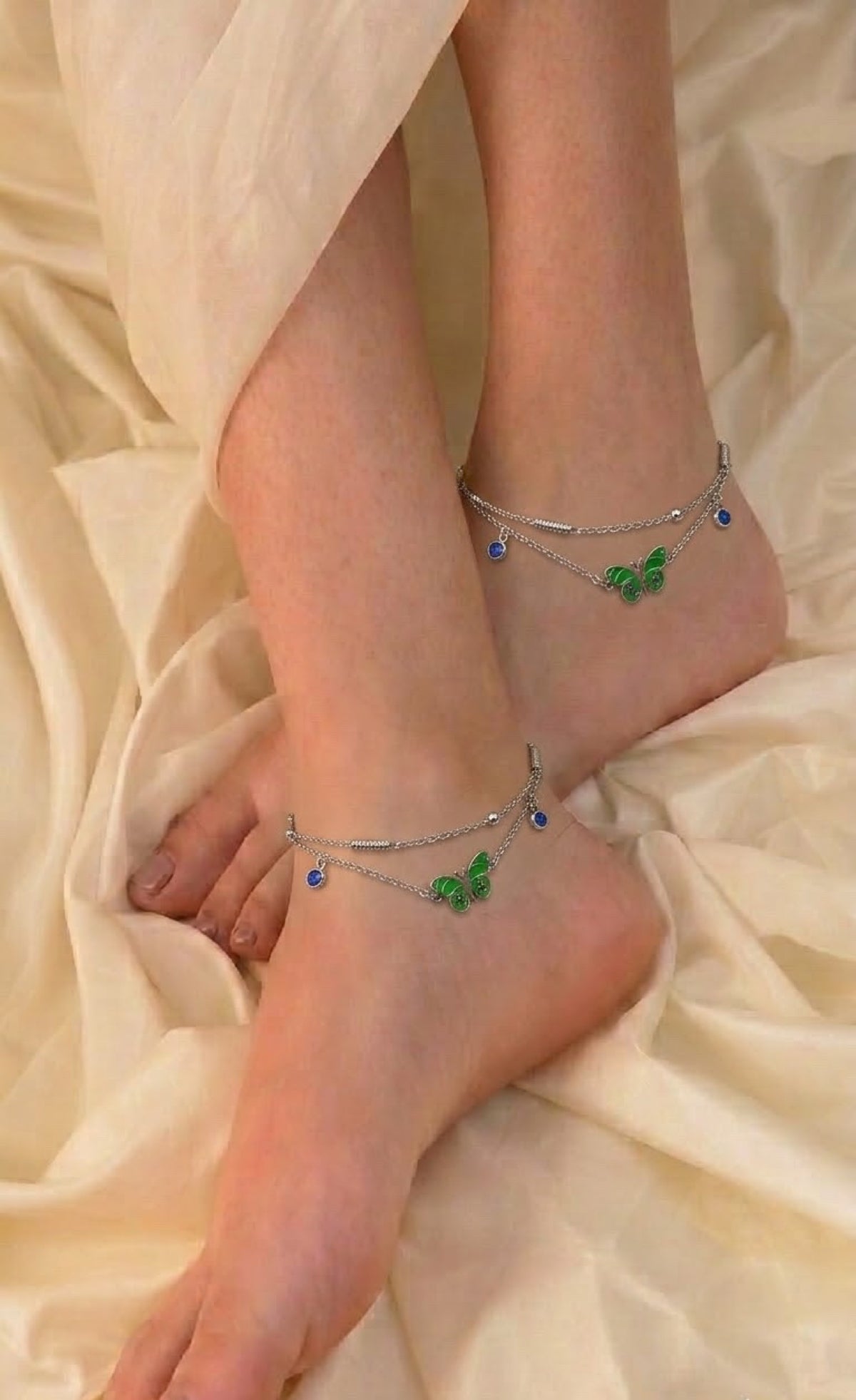 Pair of silver-tone layered anklets with green enamel butterfly and blue stones