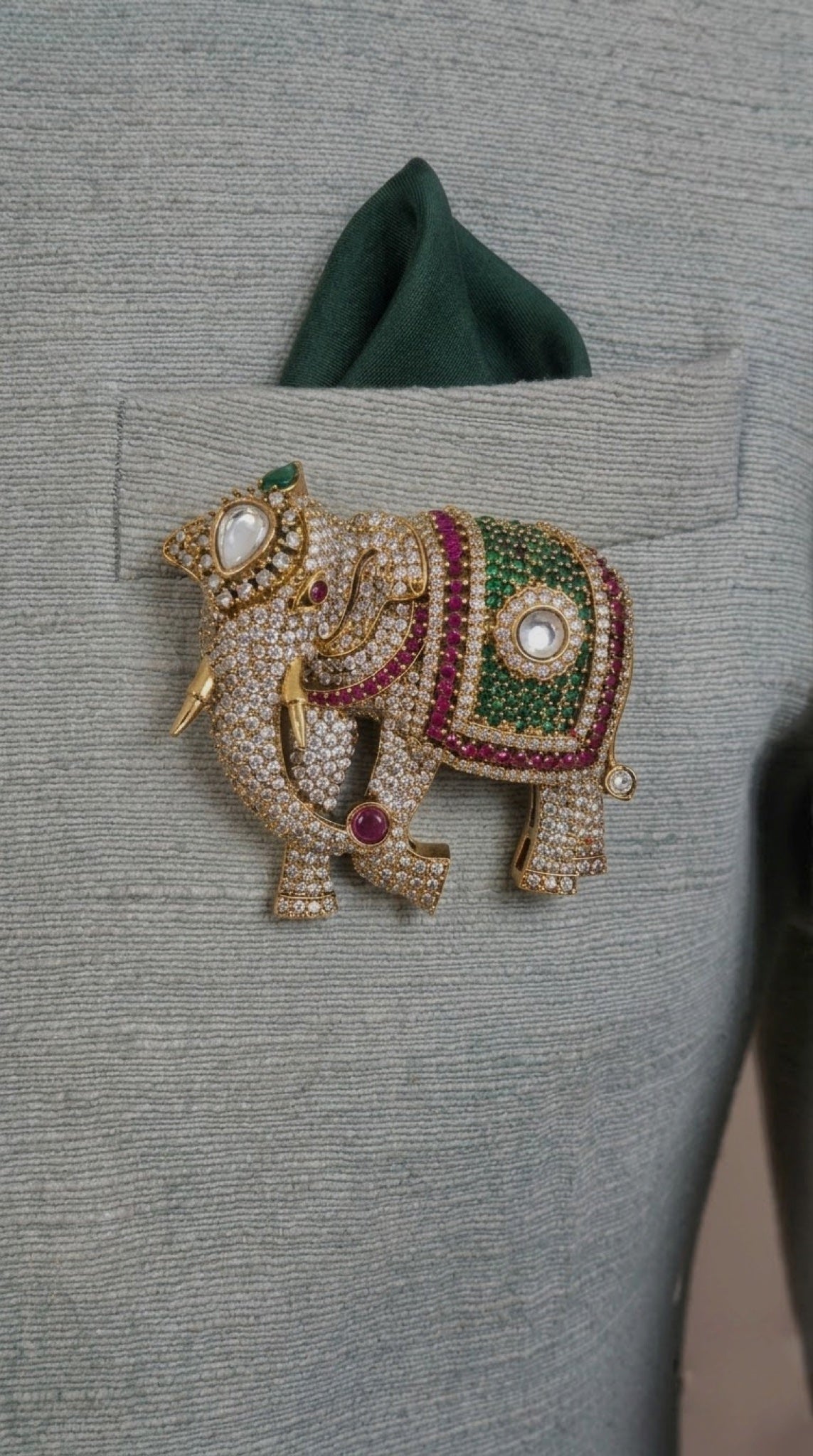 Gold-tone elephant brooch with crystal pavé and green and red stone blanket