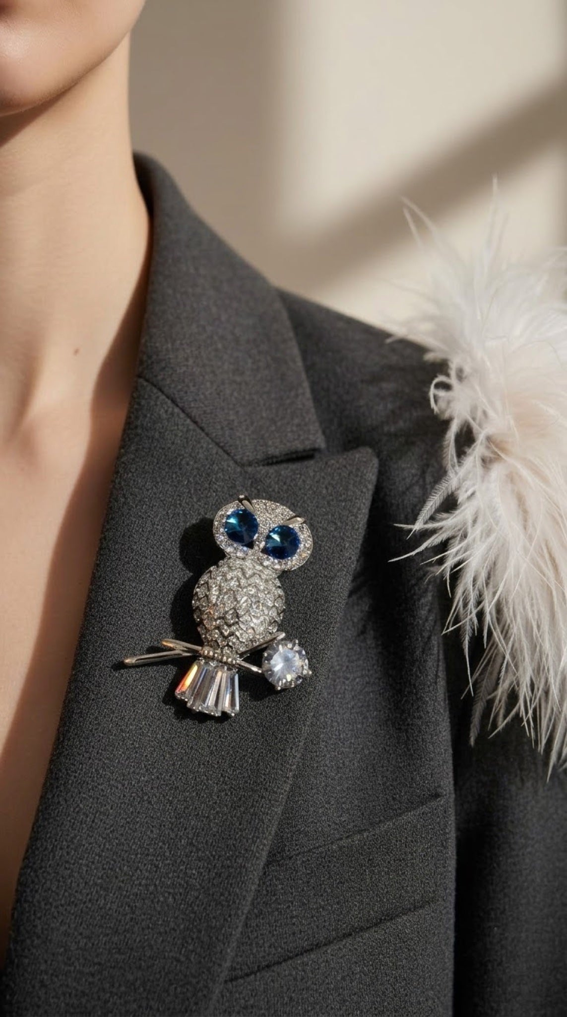 Silver-tone owl brooch with blue crystal eyes perched on a branch
