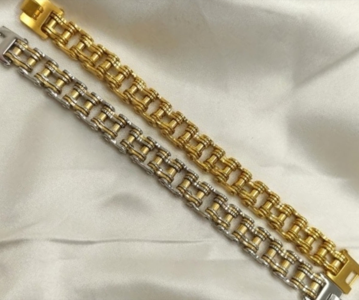 Gold-tone bike chain link bracelet with fold-over clasp on white satin