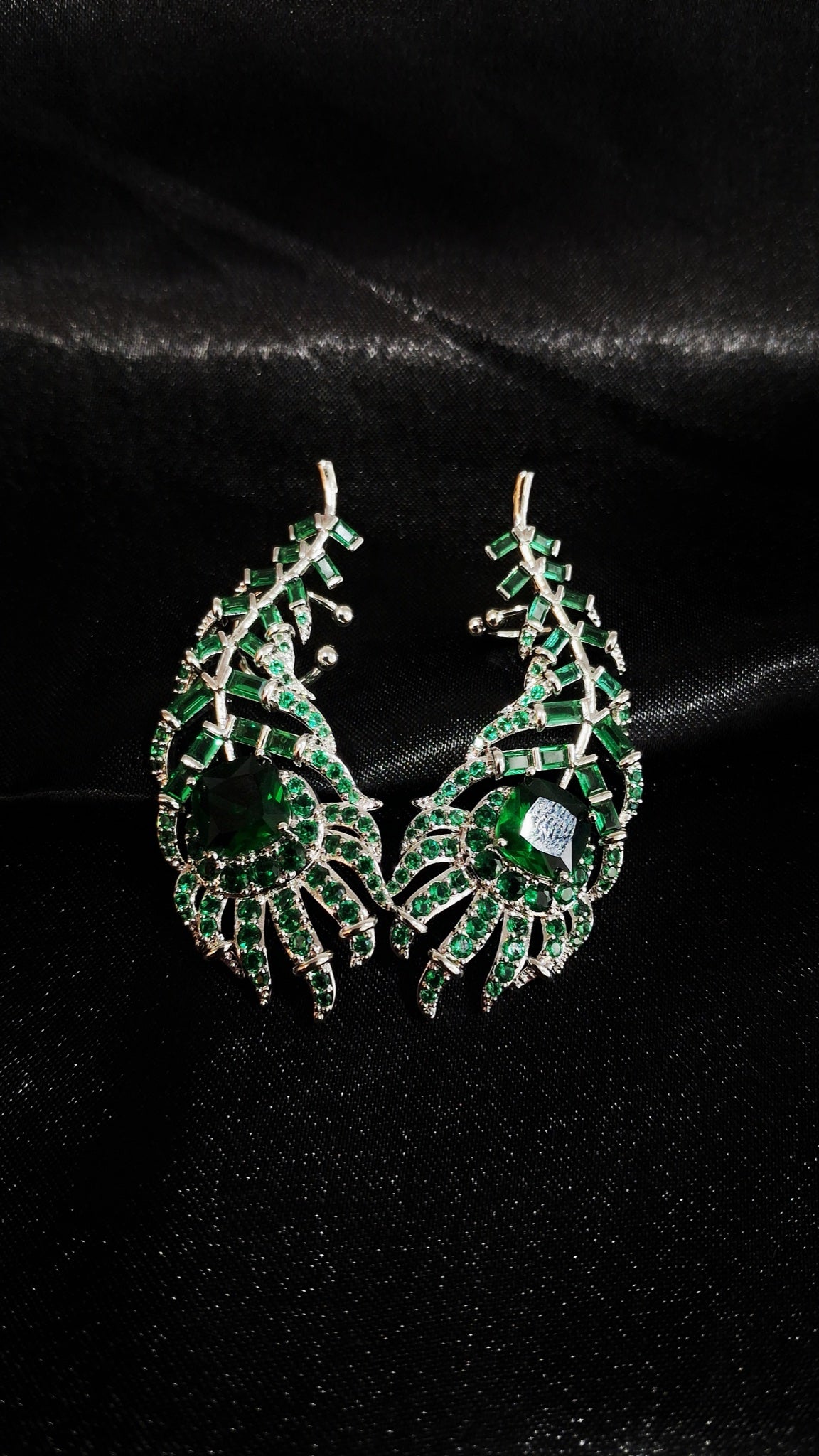 Pair of silver-tone peacock feather ear cuffs with emerald-green stones