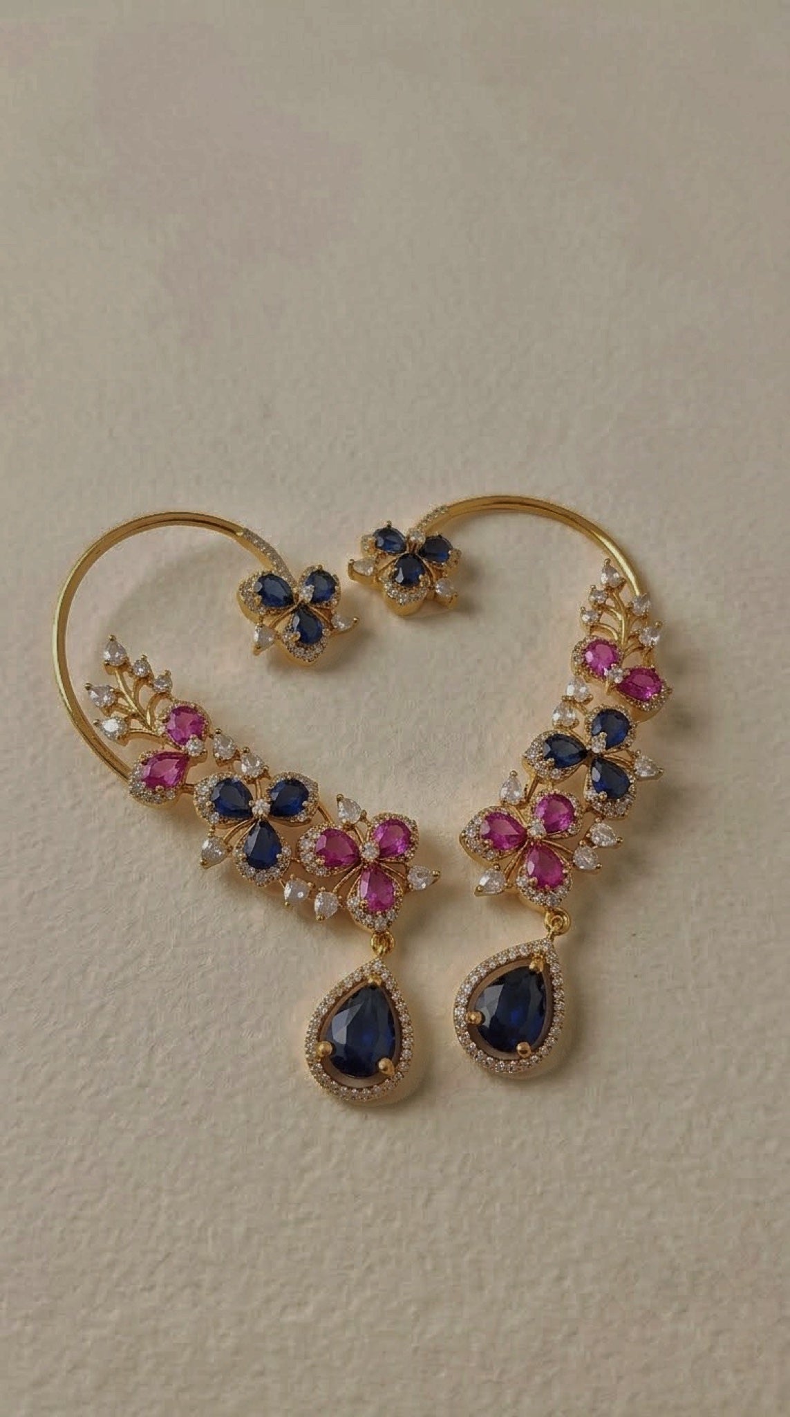 Gold-tone wire ear cuffs with pink and blue floral stones and blue teardrop drop